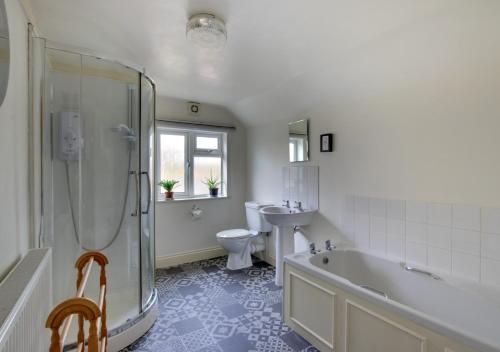 a bathroom with a tub and a toilet and a sink at Clyde Cottage in Saxmundham