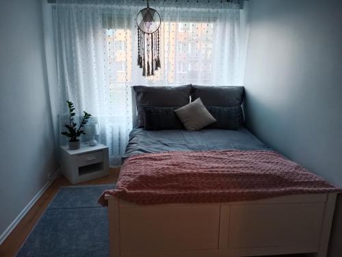 a small bedroom with a bed with a window at Noclegi Murzynowskiego in Olsztyn