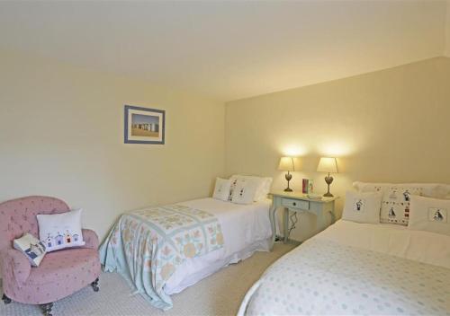 a bedroom with two beds and a chair in it at Christmas Cottage in Southwold
