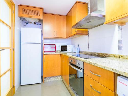 a kitchen with wooden cabinets and a white refrigerator at Apartment Vila de Oropesa X by Interhome in Oropesa del Mar
