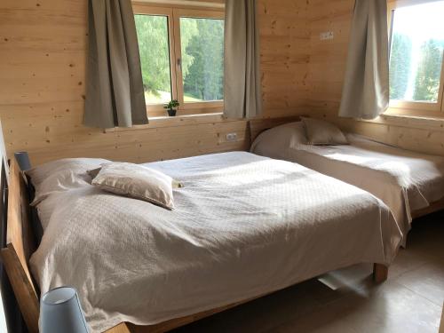 two beds in a room with two windows at Blockhaus Waldspiel in Ratten