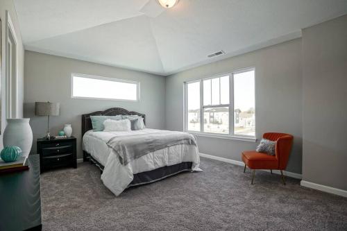 a bedroom with a bed and a chair and a window at Luxury Blue Home minutes from everything Indy in Indianapolis