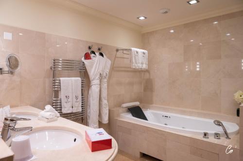 ein Badezimmer mit einer Badewanne, einem Waschbecken und einer Badewanne in der Unterkunft Georges Blanc Parc & Spa in Vonnas