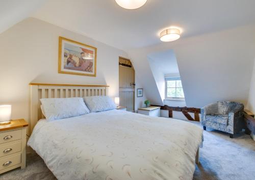 a bedroom with a large bed and a chair at Cobblers Cottage in Bramfield