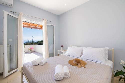 1 dormitorio con 1 cama con toallas y sombrero en R&C Corfiot house, en Achílleion