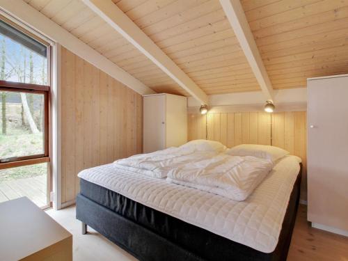 ein großes Bett in einem Zimmer mit Holzdecke in der Unterkunft Holiday Home Paulette - 450m from the sea in NW Jutland by Interhome in Løkken