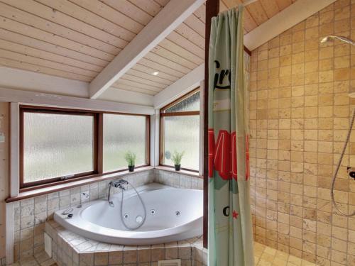 ein Bad mit einer Badewanne in einem Zimmer mit Fenstern in der Unterkunft Holiday Home Paulette - 450m from the sea in NW Jutland by Interhome in Løkken