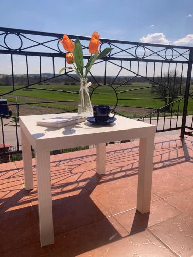 a white table with a vase with flowers on it at Apartament Villa Olivia in Szczebrzeszyn