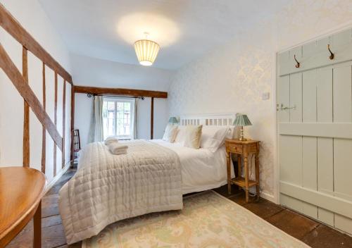 a bedroom with a bed and a table and a window at Coppers in Lavenham