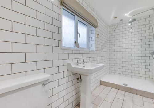 a white bathroom with a sink and a bath tub at Dakings in Halesworth