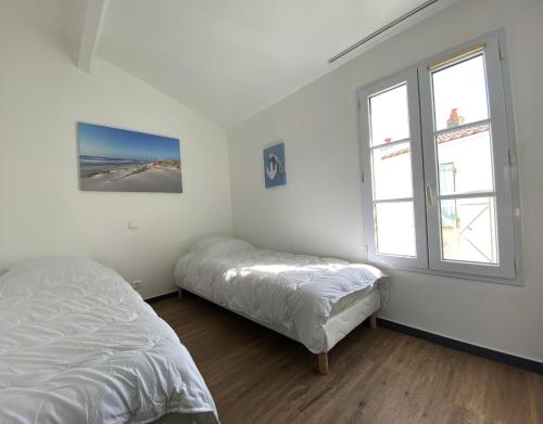 Habitación blanca con 2 camas y 2 ventanas en AGATHE Bel appartement avec piscine, en La Flotte