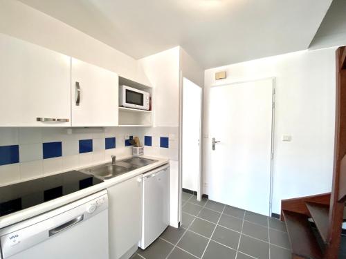 une cuisine blanche avec un évier et un micro-ondes dans l'établissement AGATHE Bel appartement avec piscine, à La Flotte