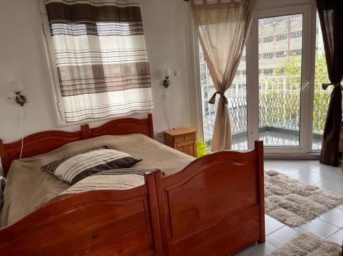 um quarto com uma cama de madeira e uma janela em Апартамент за гости Сънрайз с гледка към река Дунав em Ruse