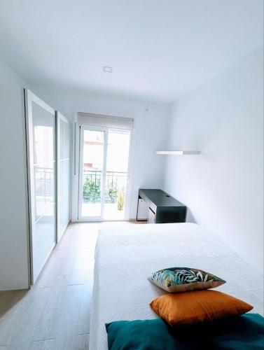 ein weißes Schlafzimmer mit einem Bett mit zwei Kissen darauf in der Unterkunft m-odern in Sevilla