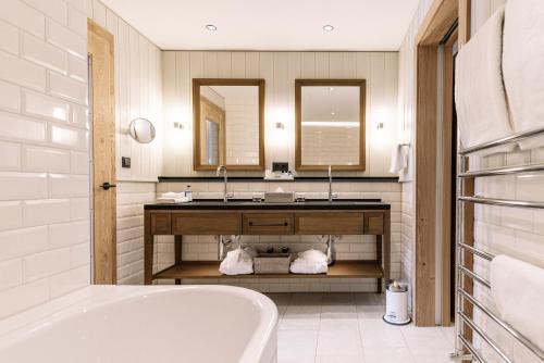 ein Badezimmer mit einer Badewanne, einem Waschbecken und einem Spiegel in der Unterkunft Löwen Hotel Montafon in Schruns-Tschagguns