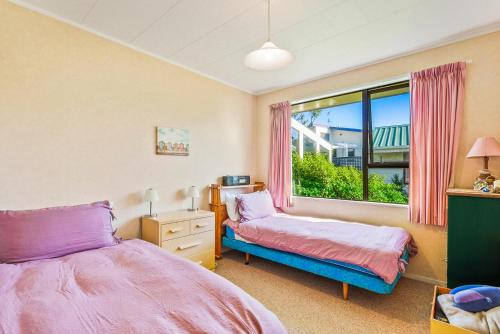 1 dormitorio con 2 camas y ventana en Waikanae Waves - Waikanae Beach Holiday Home, en Waikanae
