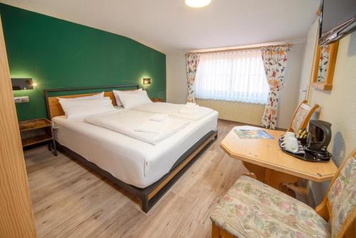 a hotel room with a bed and a desk and a table at Landgasthof Hanselewirt in Schwangau