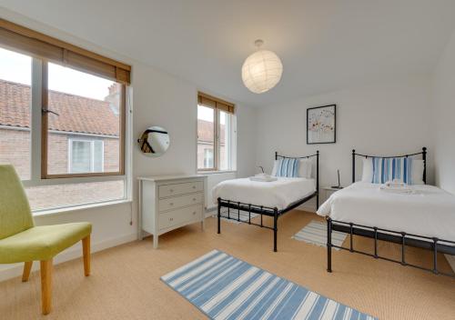 1 dormitorio con 2 camas, silla y ventana en Dunlin en Southwold