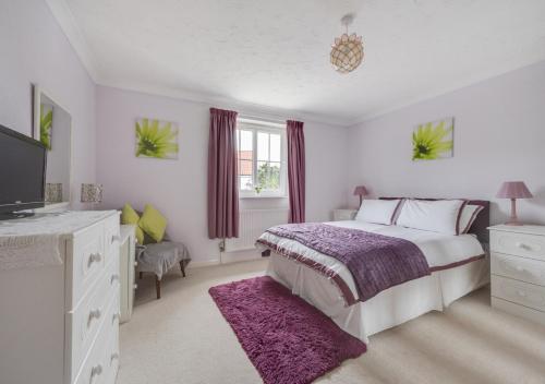 a white bedroom with a bed and a tv at Farriers in Wangford
