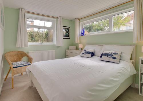 een slaapkamer met een wit bed en 2 ramen bij Fallowfield in Reydon