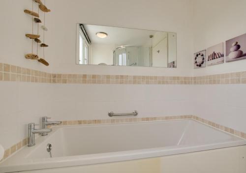 een badkamer met een wit bad en een spiegel bij Fallowfield in Reydon