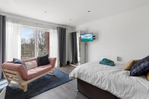 a bedroom with a bed and a chair and a television at Exeter City Centre Apartments Eden Apartment in Exeter