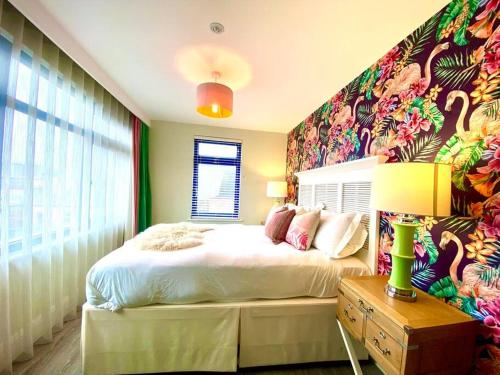 a bedroom with a large bed with a colorful wall at Stunning 3 bedroom Penthouse Apartment - Free Parking & WiFi - 1 Minute walk to Poole Quay - Great Location - Free Parking - Fast WiFi - Smart TV - Newly decorated - sleeps up to 6! Close to Poole & Bournemouth & Sandbanks in Poole