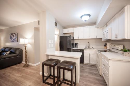 a kitchen with white cabinets and a black couch at Stay Together Suites - Spacious Condominium On The Strip Sleeps 12 - NO RESORT FEE in Las Vegas