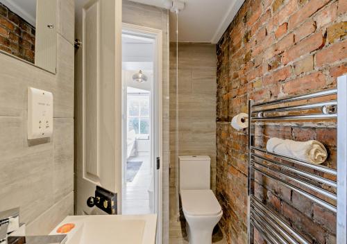 拉姆斯蓋特的住宿－Harbour Cottage - Ramsgate，浴室设有砖墙,毗邻厕所