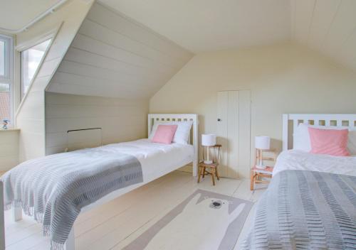 a attic bedroom with two beds and a window at Fern Cottage in Walberswick
