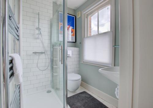 uma casa de banho com um chuveiro, um WC e um lavatório. em Fern Cottage em Walberswick