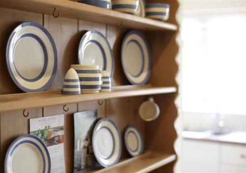 a shelf filled with plates and bowls on a wall at Heather View in Middleton