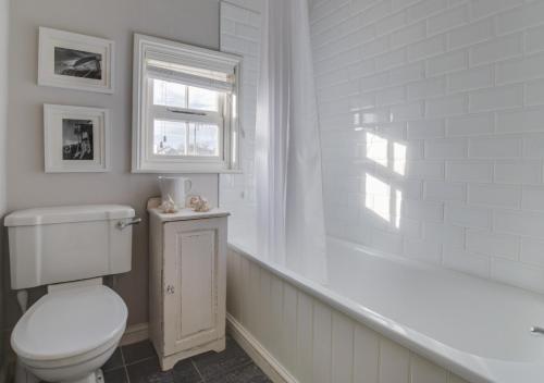a white bathroom with a toilet and a window at Hanover House in Aldeburgh