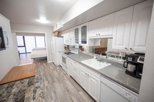 a kitchen with white cabinets and a white refrigerator at Stay Together Suites - Stylish Condominium On The Strip Sleeps 12 - NO RESORT FEE in Las Vegas
