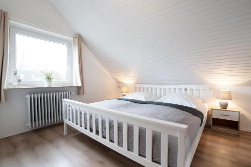 een witte wieg in een slaapkamer met een raam bij Erlengrund 7 Leuchtturm in Pelzerhaken