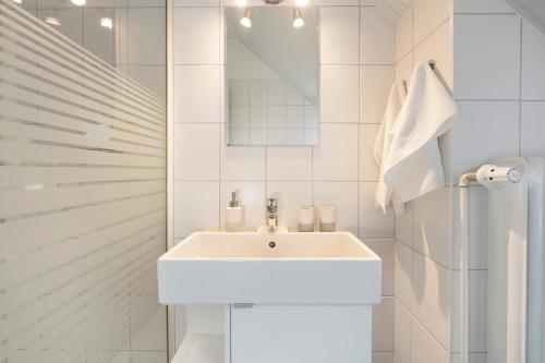 a white bathroom with a sink and a shower at Erlengrund 7 Leuchtturm in Pelzerhaken