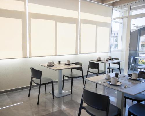 una sala da pranzo con tavoli, sedie e finestre di LAURIA Luxury Room a Gela