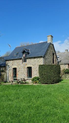 a stone house with a black roof on a grass field at L'AUBERGE DE LA PORTE in Saint-Jouan-des-Guérets