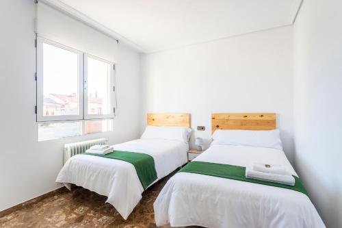 two beds in a white room with a window at Casa Las Rosas in Iniesta