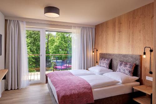 a bedroom with a large bed and a large window at HOTEL SONNBLICK Kaprun Salzburg - incl Zell am See-Kaprun Summercard in Kaprun