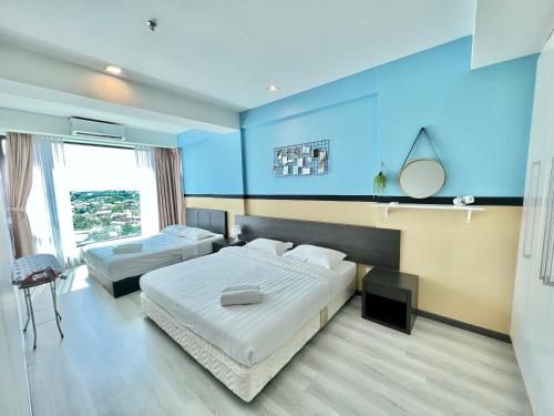 a bedroom with two beds and a blue wall at Cozy Living Sky Apartment in Kota Kinabalu