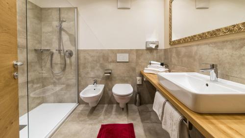 ein Badezimmer mit Waschbecken, Toilette und Dusche in der Unterkunft Hotel Scherer in Olang