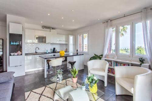 Il dispose d'une cuisine et d'un salon avec des meubles blancs et des fenêtres. dans l'établissement L27 2P Jasmins Sea View Parking & AC, à Nice