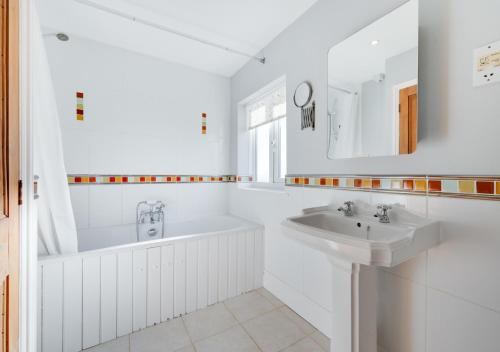 a white bathroom with a tub and a sink at Hightide in Southwold