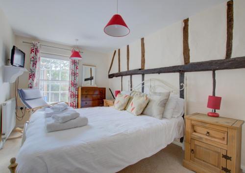 um quarto com uma grande cama branca e uma janela em Horseshoe Cottage em Southwold