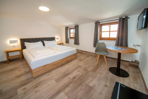 a bedroom with a bed and a desk and a table at Landgasthof Hanselewirt in Schwangau
