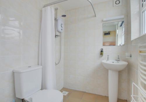 a white bathroom with a toilet and a sink at Horseshoe Cottage in Southwold