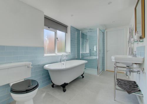 a bathroom with a tub and a toilet and a sink at James Cottage in Southwold