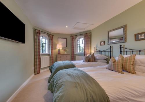 a bedroom with two beds and a flat screen tv at Ivy Lodge in Rendlesham