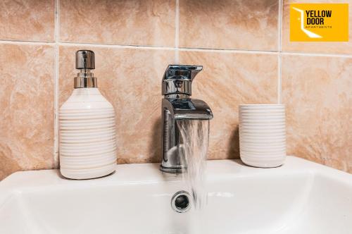 a bathroom sink with a faucet and a bottle of water at Kingscross Neuk - City Base in Dundee